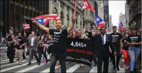  ??  ?? Bronx Borough President Ruben Diaz (center) leads a group of state and city officials during the Puerto Rican Day Parade on Sunday, in New York. Their shirts and banner with “4,645” represents the under-reporting of the death toll after after Hurricane...