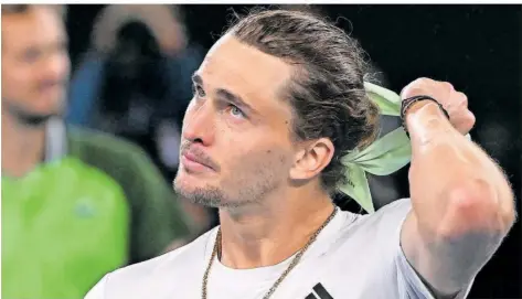  ?? FOTO: WEST/AFP ?? Frustriert und geschockt zieht Alexander Zverev sein Haarband nach dem Matchball aus, während im Hintergrun­d Daniil Medwedew zufrieden ist.