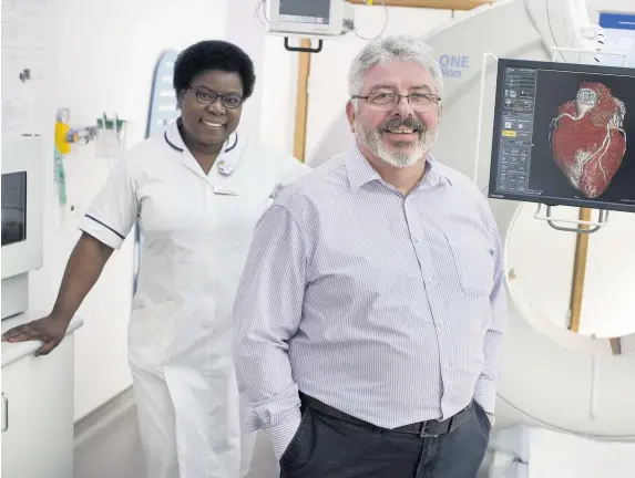  ??  ?? > Colin Thomas with CT superinten­dent radiograph­er, Charity Mukwenya, at St Joseph’s Hospital, Newport