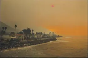  ?? Ap photo ?? Homes stand along the beach as the sun is visible through thick smoke from a wildfire Wednesday in Ventura, Calif.