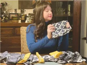  ?? BOB RZADZKI VIA AP ?? Rachel Cooper of Chicago folds the cloth napkins she purchased to replace paper napkins for daily dining.