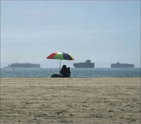  ?? Jae C. Hong Associated Press ?? A PERSON lounges in Seal Beach as container ships wait to dock at the L.A. and Long Beach ports. On Tuesday, Rep. Michelle Steel (RSeal Beach) introduced legislatio­n seeking to ban cargo ships idling or anchoring 24 nautical miles or less off the Orange County coast.