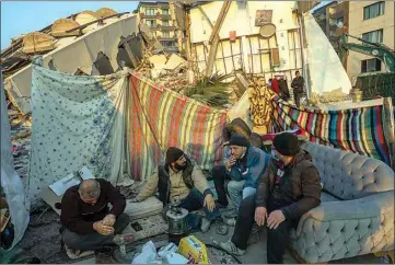  ?? BERNAT ARMANGUE / AP ?? Men sit in front of the rubble of an area destroyed during the earthquake in Antakya, southeaste­rn Turkey, Sunday.