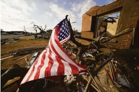  ?? Gerald Herbert / Associated Press ?? An American flag flies amidst debris of destroyed homes after tornadoes tore through Mayfield, Ky. The town suffered some of the worst damage.