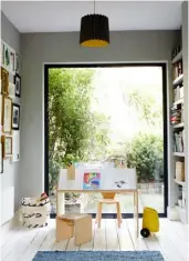  ??  ?? LET THE LIGHT IN In the play area, floor-to-ceiling picture windows bring the outside in. An Astroturf lawn, visible through the glass, is a favourite place for the kids to play. The ‘house desk' came from Olive Loves Alfie and the rug is from La Redoute.➺