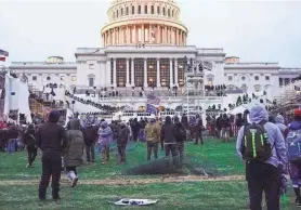  ?? JULIO CORTEZ/AP FILE ?? Rioters walk on the West Front at the U.S. Capitol on Jan. 6, 2021. Democracy scholars are warning that political parties must accept the results of fair elections, reject violence and break ties to extremists.