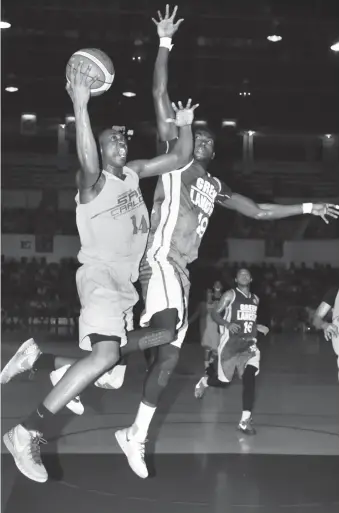  ?? PAUL JUN E. ROSAROSO ?? University of San Carlos Warriors’ Shooster Olago drives to the basket against Steve Cedric Akomo of the University of the Visayas Green Lancers in Game 3 of their CESAFI men’s basketball finals last night at the Cebu Coliseum.