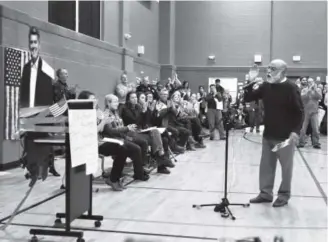  ??  ?? Arvada resident Ahmad Ghais on Friday gestures toward a cardboard cutout of U.S. Sen. Cory Gardner while recording an address to the Republican from Colorado at Byers Middle School in Denver during an “in absentia” town hall meeting. Photos by Andy...