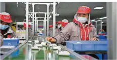  ?? FOTO: XUE YUGE/XINHUA/DPA ?? Menschen arbeiten in einer Fabrik in China am Fließband. Oft lassen sich die langen Produktion­swege kaum zurückverf­olgen.