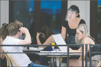  ?? GRAHAM HUGHES/THE CANADIAN PRESS ?? A server wears a face shield as she takes an order at a restaurant in Montreal, yesterday, as the COVID-19 pandemic continues in Canada and around the world.