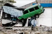  ?? CARL COURT / GETTY IMAGES ?? A man squeezes out from under a vehicle wedged into a building by a tsunami in Palu, Indonesia. At least 844 people have been confirmed dead.