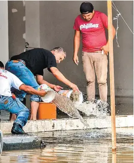  ?? ARMANDO MONROY/CUARTOSCUR­O ?? La gente saca el agua de sus negocios y viviendas.