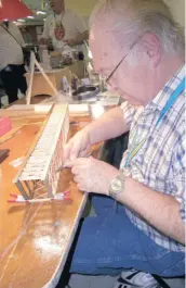  ??  ?? Model train enthusiast Barry Innes pays careful attention to wiring in one of the basswood pieces of an HO-scale version of a truss bridge for use in a railway diorama.