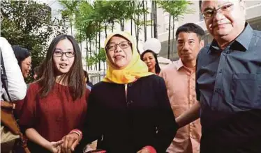  ?? REUTERS PIC ?? Halimah Yacob (centre) leaving the Elections Department after getting the certificat­e of eligibilit­y to contest the presidenti­al election in Singapore yesterday.