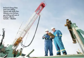  ?? EnCana's Doug Shea goes over drilling reports with driller Ron Webster at an EnCana gas drilling well east of Calgary, Alberta. Canada. — Reuters ??