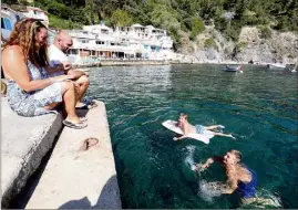  ??  ?? Les enfants passent une bonne partie de la journée dans l’eau, devant le quai, au pied des cabanons.