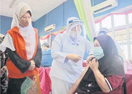  ??  ?? Fatimah observes the vaccinatio­n process of a resident at Desa Bina Diri Kuching.