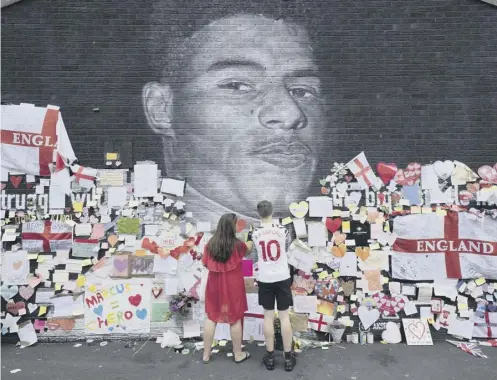  ??  ?? 0 Mackenzie Robertson and his mother Sally Coles-roberton place a message of support on the repaired Marcus Rashford mural