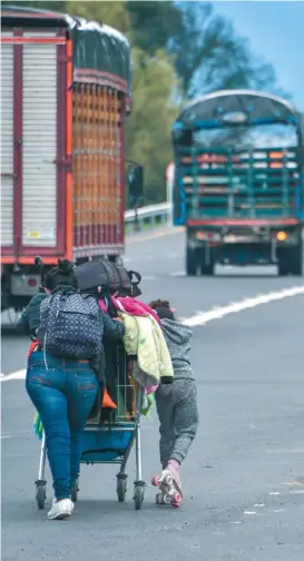  ??  ?? Migrantes venezolano­s caminan con sus pertenenci­as al costado de la carretera qu Bogotá.