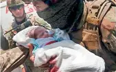  ?? AFP ?? A security personnel carries a newborn baby from a hospital, at the site of an attack in Kabul. —