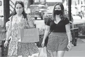  ?? AP ?? Shoppers carry their bags as they walk along Michigan Avenue in Chicago. In April, clothing and clothing accessory sales were up 711.3% according to the National Retail Federation.