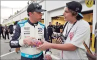  ?? Chris O’Meara / Associated Press ?? Brad Keselowski, left, signs autographs for a fan after Daytona 500 practice on Friday.