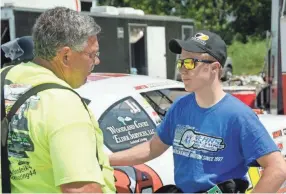  ?? DAVE KALLMANN / MILWAUKEE JOURNAL SENTINEL ?? Justin Mondeik, 21, of Gleason, talks with a crew member during practice Monday at Slinger Speedway.