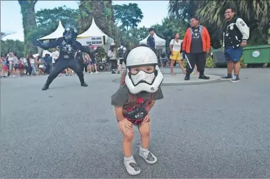  ?? ROSLAN RAHMAN/ AGENCE FRANCE-PRESSE ?? A young fan wearing a stormtroop­er mask looks on during a festival marking Star Wars Day in Singapore on Thursday. Fans of the film franchise celebrate annually on May 4 with food, fun — and marathon screenings.