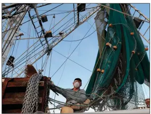  ?? (AP/Gerald Herbert) ?? Minh Nguyen cleans his shrimp boat in Morgan City, La. He said he will not be taking the boat out for the start of shrimping season because of low shrimp prices amid the coronaviru­s.