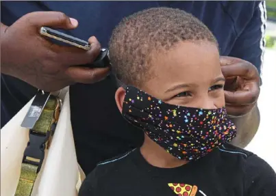  ?? Darrell Sapp/Post-Gazette ?? Taneisha Freeman, of Pittsburgh, helps her son Davion Maynor, 5, adjust his new mask in Arlington Heights on Friday, when the Minority Emergency Preparedne­ss Task Force distribute­d kits with masks, hand sanitizer and informatio­n about COVID-19.