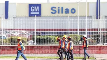  ??  ?? General Motors workers are seen while leaving their shift, outside the GM pickup and transmissi­on plant in Silao, Mexico.