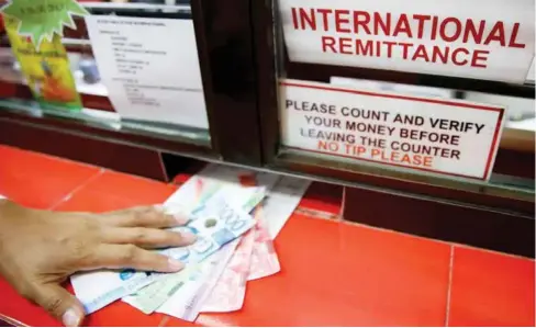  ?? REUTERS ?? Philippine peso bills sent by a Filipino working abroad are pictured being received by a relative at a money remittance center in Makati City, Metro Manila.