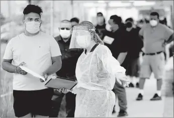  ?? MARCIO JOSE SANCHEZ/AP ?? People line up behind a health care worker at a mobile testing site July 22 in Los Angeles. Early studies that compare different countries’ responses are finding that U.S. shortages of masks, gloves, gowns, shields and testing kits cost lives.