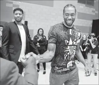  ?? Wally Skalij Los Angeles Times ?? IT WAS A DAY for smiles as Kawhi Leonard shakes hands with a fan while Paul George watches at their introducto­ry news conference at Green Meadows Recreation Center.