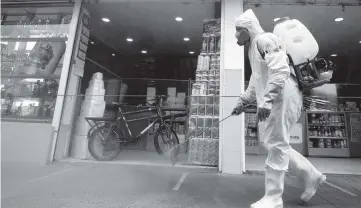  ?? FERNANDO VERGARA AP ?? A worker in full protective gear disinfects a sidewalk at Corabastos, one of Latin America's largest food distributi­on centers, in Bogota.