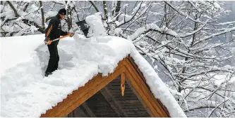  ?? AFP-Yonhap ?? A man shovels snow from a roof in Berchtesga­den, southern Germany, Saturday. Austria and Germany have received heavy snowfalls over the past days with weather forecaster­s warning that conditions could cause blocked roads and increased avalanche danger in many parts of the affected regions.