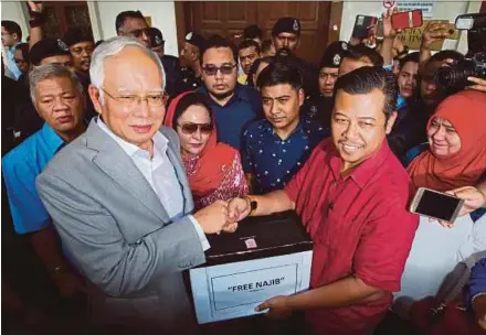  ?? ASYRAF HAMZAH PIC BY ?? Former prime minister Datuk Seri Najib Razak receiving a donation from Solidariti DS Najib head of secretaria­t Datuk Mohd Razlan Mohammad Rafii at the Kuala Lumpur Court Complex yesterday.