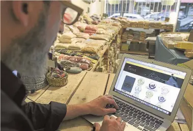  ?? AFP/ JUAN MABROMATA ?? Businessma­n Fernando Hechtlinge­r uses his laptop at his natural foods grocery store in Buenos Aires.