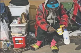  ??  ?? A man sits with his belongings in Kensington after receiving a lunch bag from The Grace Project.