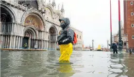  ?? Photo / AP ?? People wade their way through water in flooded St Mark’s Square following a high tide, in Venice, Italy.