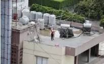  ??  ?? A woman does some stretching exercises on the rooftop of her building