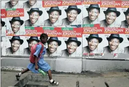  ?? PHOTO: REUTERS ?? A schoolgirl walks past campaign posters in support of Nigeria's President Goodluck Jonathan. The election will have implicatio­ns far beyond Nigeria’s borders.