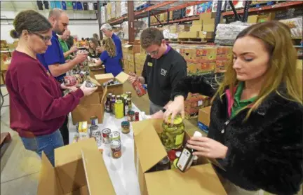  ?? PETE BANNAN — DIGITAL FIRST MEDIA ?? Downingtow­n Wegmans Food Markets employees Michele Fowler, Michael and Shelbey Nelson volunteer by sorting and packing boxes of food donated by Wegman’s for the Chester County Food Bank. Wegmans also presented a check for $152,789 from the Downingtow­n and Malvern stores to the food bank.