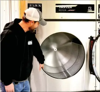  ?? TIMES photograph by Annette Beard ?? Brentley Bone, owner of the Battlefiel­d Laundromat, shows the size of an 80-pound dryer.