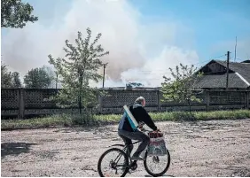  ?? DIMITAR DILKOFF AFP VIA GETTY IMAGES ?? A man rides by burning storage buildings that contain agricultur­al products after they were hit by Russian forces Wednesday in the town of Orikhiv, near Zaporizhzh­ia.