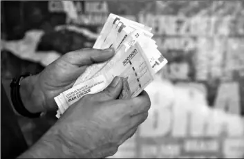  ?? AP Photo/Ebrahim Noroozi ?? In this 2019 file photo, a man counts his banknotes and traveler checks in Tehran, Iran.