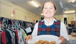  ??  ?? Tempting treat: Nadia Luketina from Holy Family School is on handout duties to the charity shop customers.