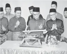  ??  ?? Dr Annuar (front, second right) breaks open the ‘lemang’ (glutinous rice cooked in bamboo) to mark the start of the event.