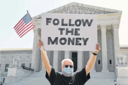  ?? REUTERS ?? Bill Christeson holds a sign reading “follow the money” in anticipati­on of justices ruling on U.S. President Donald Trump’s bid to block his financial records from being obtained by third parties, outside the U.S. Supreme Court in Washington.