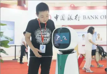  ?? A JING / FOR CHINA DAILY ?? A child interacts with Bank of China's robot receptioni­st during the 25th China Internatio­nal Financial Exhibition in Beijing.